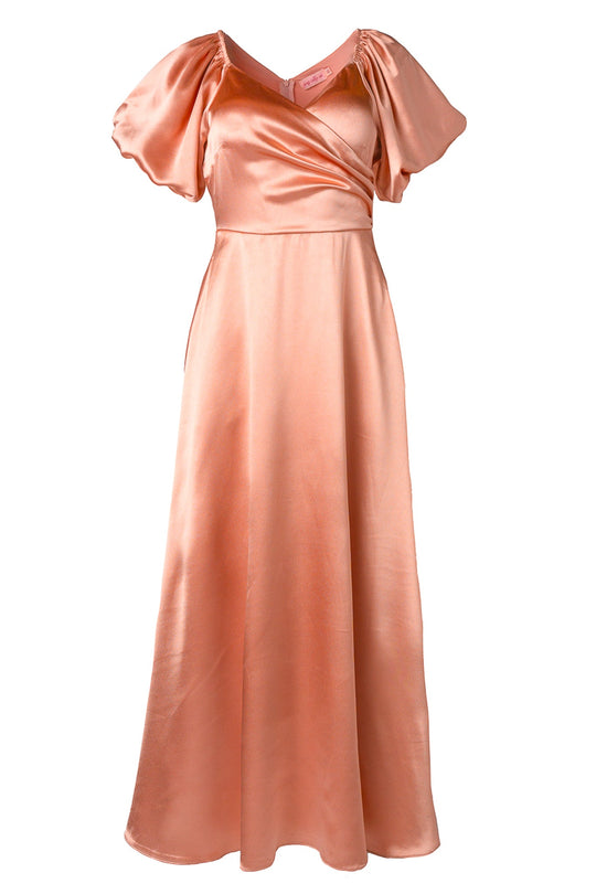 The Tessie Dress in Apricot Crush by Ivy City Co features peach-colored satin, short puff sleeves, a V-neckline, and a wrap-style bodice. Its nursing-friendly design is completed with a long, flowing A-line skirt for an elegant and formal look.