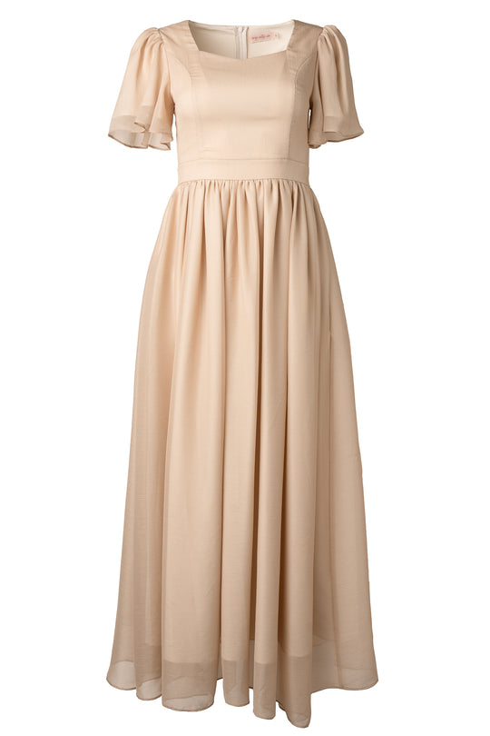The Abbie Dress in Champagne by Ivy City Co is a long, elegant maxi with short puff sleeves, a fitted bodice, and a flowing gathered skirt crafted from light, sheer fabric.