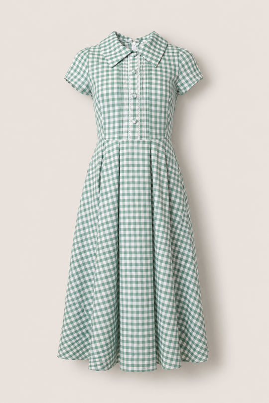 The Amber Dress in Sage Gingham by Ivy City Co features short sleeves, a collared neckline, button-down front, fitted waist, and pleated cotton skirt, showcased on a plain light background.