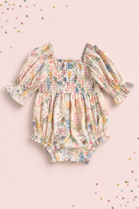 The Ivy City Co Baby Madeline Romper in Cordelia Floral features long puffed sleeves, ruffled cuffs, and a smocked bodice on pale pink with pastel confetti dots—perfect for adorable mommy-and-me moments.