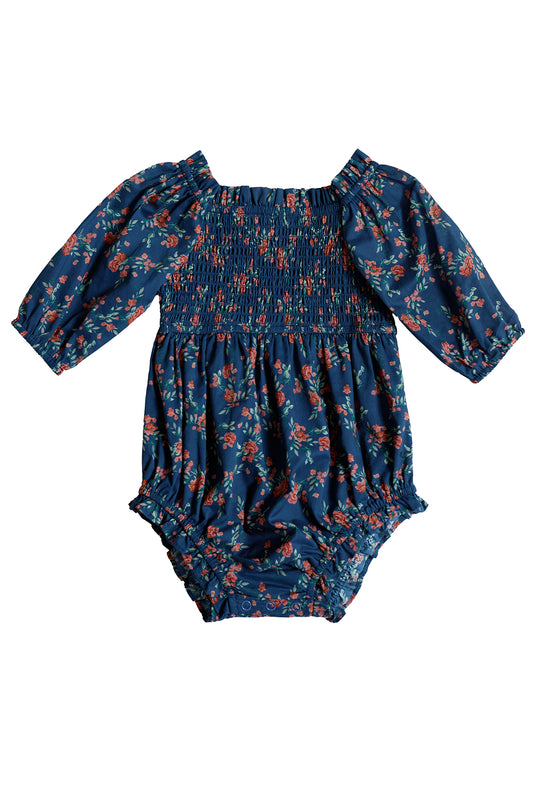 The Ivy City Co Baby Madeline Romper in Midnight Vibrant Chintz is a dark blue long-sleeve floral print romper with a smocked bodice plus elasticized cuffs and leg openings.