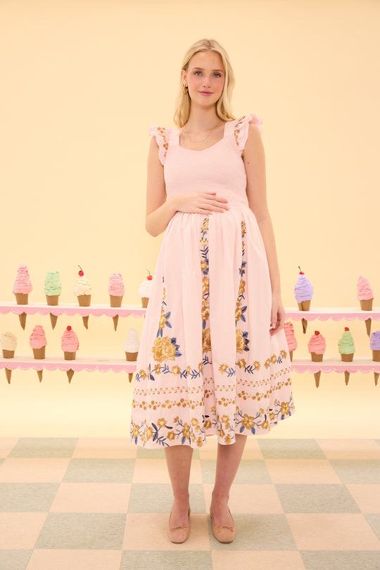 Woman wearing a pink dress with floral patterns in front of an ice cream cone display.