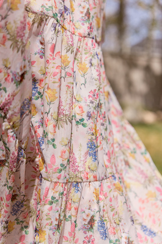 Close-up of the Ivy City Co Imogen Dress in Cordelia Floral—a flowy chiffon maxi with colorful florals in pink, yellow, blue, and green. Maternity friendly and photographed outdoors in gentle sunlight.