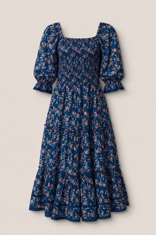 The Madeline Dress in Midnight Vibrant Chintz by Ivy City Co features a navy floral print, smocked bodice, puffed half sleeves, ruffled tiered skirt, and scalloped hem—an ankle-length maternity-friendly dress for any occasion.