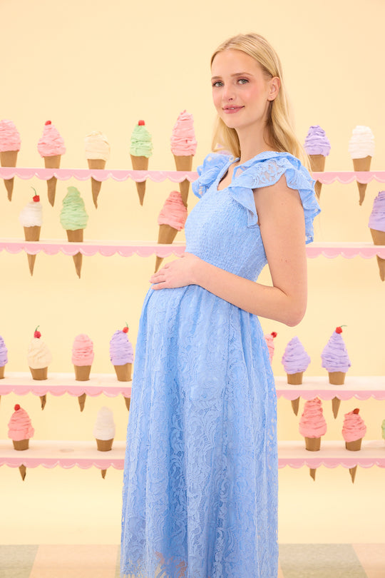 Woman in a blue dress standing in front of an ice cream cone patterned wall.