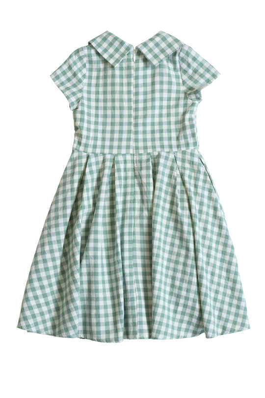 The Mini Amber Dress in Sage Gingham by Ivy City Co features light green and white gingham, short sleeves, a fitted bodice, wide collar, and pleated skirt, shown against a white background.