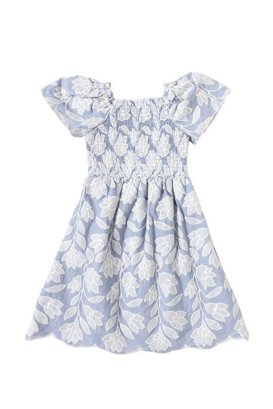 The Mini Ophelia Dress in Mosaic Embroidery by Ivy City Co features a light blue hue, smocked bodice, ruffled sleeves, white floral patterns, and a flared skirt with mosaic white leaf and flower embroidery—perfect for Mom and Me matching.