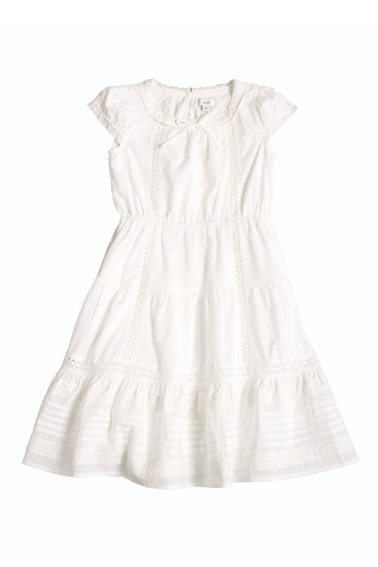 The Ivy City Co Mini Palermo Dress in White features a smocked bodice, short puff sleeves, lace trim, gathered waist, and a ruffled hem, shown laid flat on a white background.