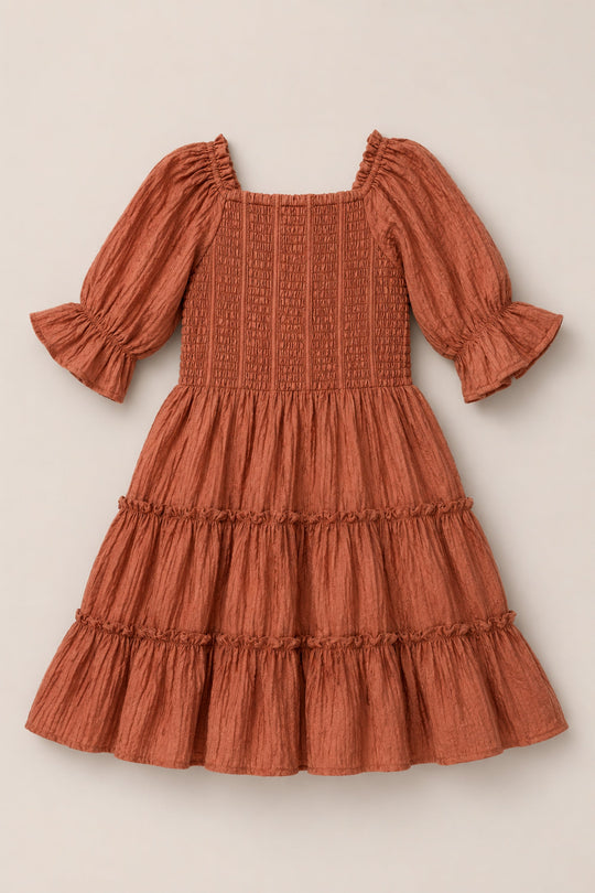 The Ivy City Co Mini Madeline Dress in Apple Cider, featuring a smocked bodice, three-quarter puff sleeves with ruffled cuffs, and a tiered ruffled skirt, is displayed flat on a neutral background.
