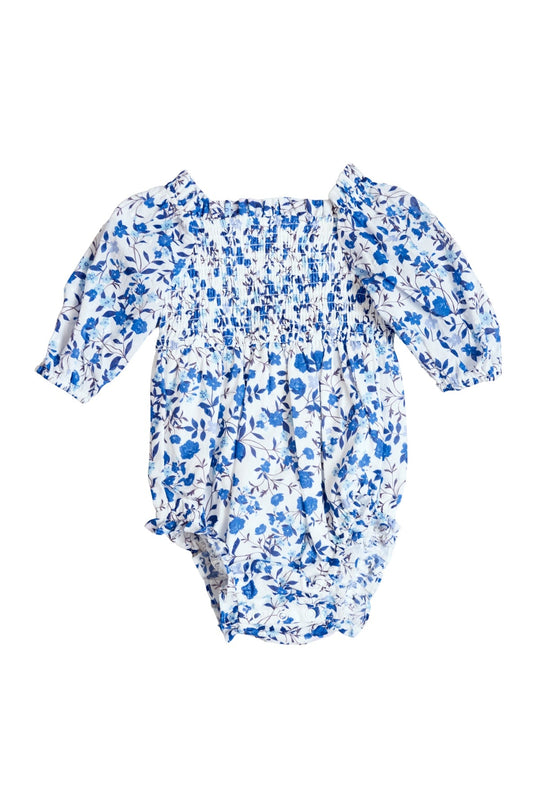 The Ivy City Co Baby Madeline Romper in Ditsy Cobalt Floral features a blue and white ditsy floral print with a smocked bodice, long puffed sleeves, and elastic leg openings, shown on a white background.
