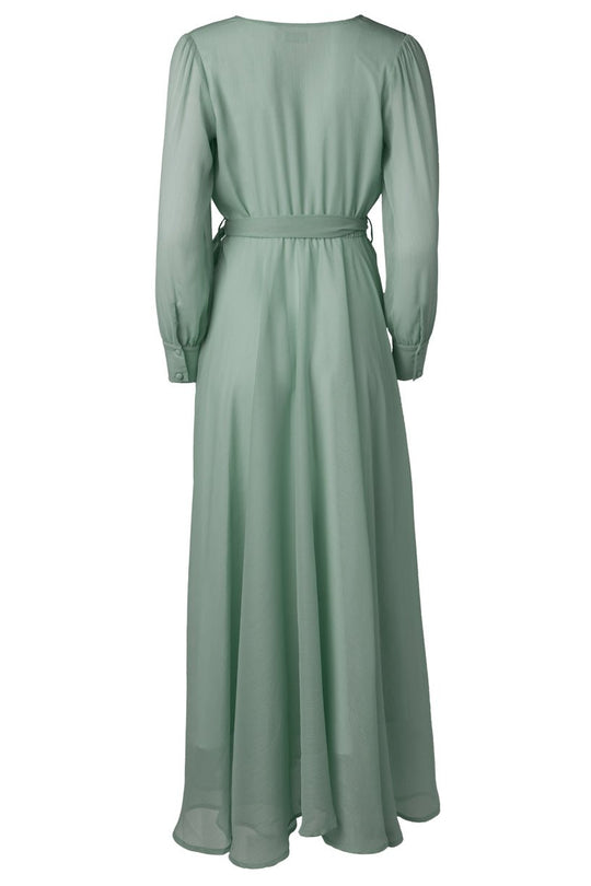 The Andie Dress in Sage by Ivy City Co is a long, light green maxi dress featuring long sleeves, a fitted waist accented with a thin belt, and a flowing skirt shown from the back. Crafted from lightweight, slightly sheer fabric, it’s an elegant choice for bridesmaids.