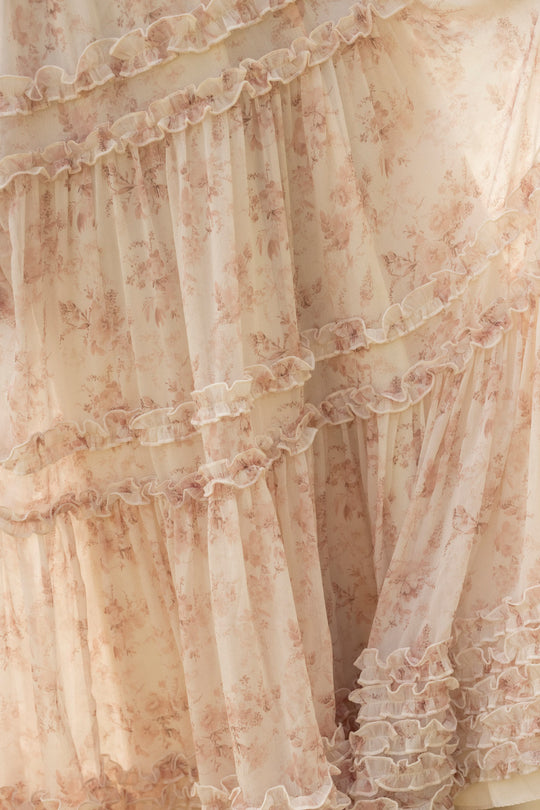 Close-up of the Geneva Dress in Banana Creme Aquarelle Fleur by Ivy City Co, featuring light pink, sheer fabric with a delicate floral pattern and layered ruffles for a soft, flowy, romantic, vintage-inspired look.