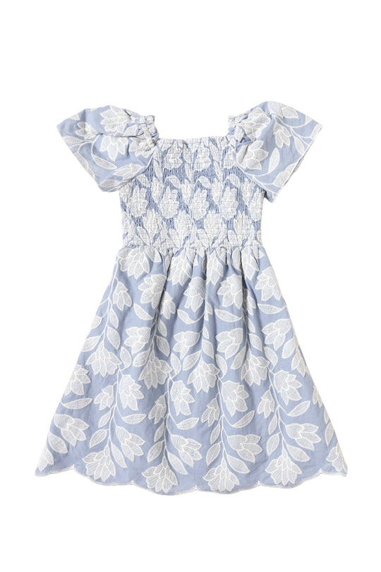 The Mini Ophelia Dress in Mosaic Embroidery by Ivy City Co is a light blue dress for children, featuring short ruffled sleeves and a smocked bodice. Adorned with an all-over white floral and leaf pattern reminiscent of mosaic embroidery, this dress offers a soft, delicate look—perfect for charming Mom and Me matching moments.