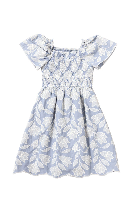 The Mini Ophelia Dress in Mosaic Embroidery by Ivy City Co is a light blue girls’ dress featuring white floral mosaic embroidery, short puffed sleeves, and a smocked bodice. The knee-length skirt showcases bold white embroidered floral patterns, making it ideal for special occasions or coordinating Mom and Me looks.